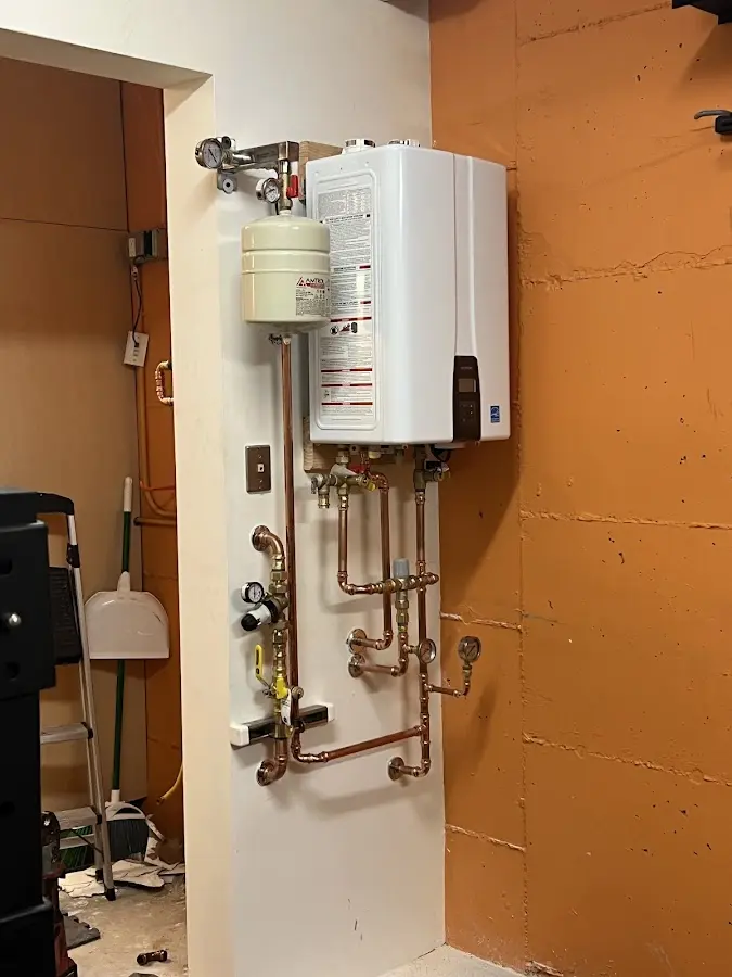 Plumbing technician inspecting water heater connections in Tontitown